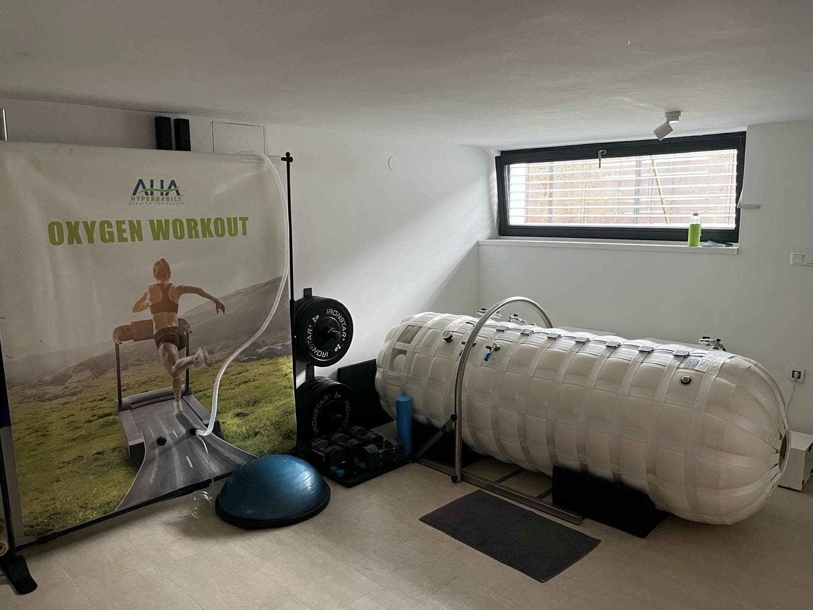 Notranjost studia O₂Boost v Ljubljani — hiperbarična komora s pripravljeno opremo za trening.